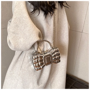 Detail of silver bow-shaped acrylic clutch bag with metal chain strap and top handle