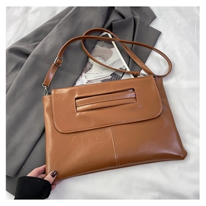 Close-up of caramel brown leather handbag with unique cutout flap handle and silver hardware