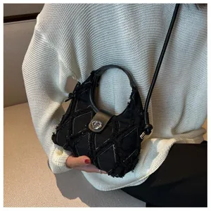 Detail of black quilted denim bag with frayed edges and silver twist lock closure