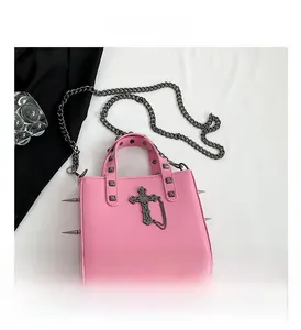 Close-up of pink punk handbag with silver rivets, spikes and black cross charm