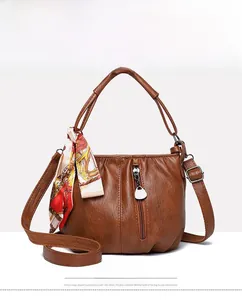 Front view of a brown pleated handbag featuring a decorative printed scarf on the handle