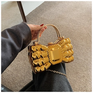 Detail of a gold bow-shaped evening bag with crystal handle and metallic texture