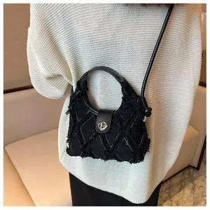Detail shot of black quilted crossbody bag with silver metal buckle on a white knit sweater