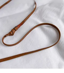 Gros plan sur la bandoulière en cuir marron avec nœuds décoratifs et coutures dentelées