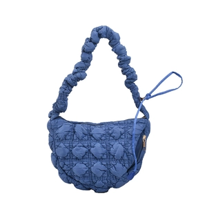 Blue quilted puffer hobo bag with a crescent shape and textured surface on white background