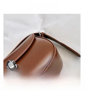 Vista macro di borsa in pelle marrone con chiusura rotante in metallo argento e cuciture