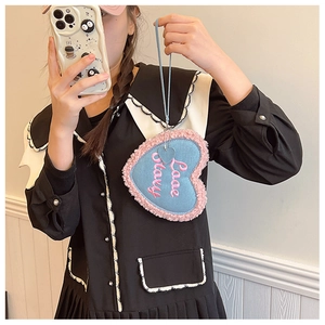 Détail d'un charme en peluche en forme de cœur avec broderie Love Story et fausse fourrure rose