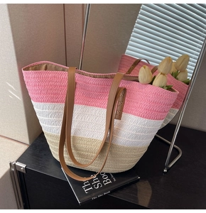 Detail of multi-color woven straw bucket bag with brown leather handles and fine stitching