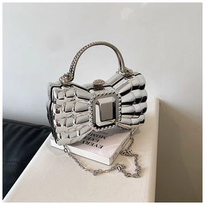Detail of silver mirror bow-shaped evening clutch bag with metal chain and top handle