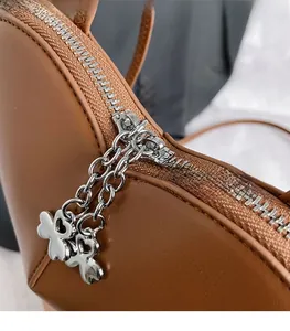 Vue macro des zips en forme de cœur sur une bandoulière en cuir marron foncé