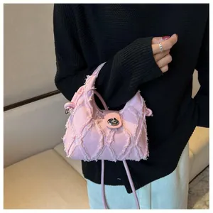 On-body view of a pink denim crossbody bag with quilted texture and silver twist lock