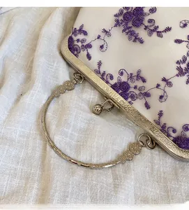 Detail of vintage metal handle and floral embroidery on a white mesh evening bag