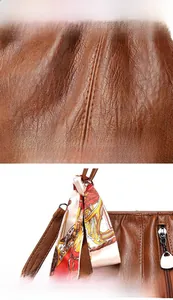 Close-up of brown lychee texture leather handbag with colorful silk scarf on the handle