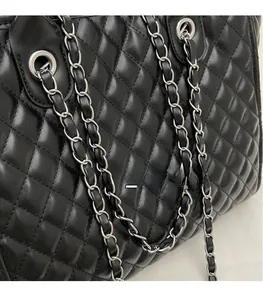 Detailed macro view of black quilted leather texture and silver chain shoulder strap