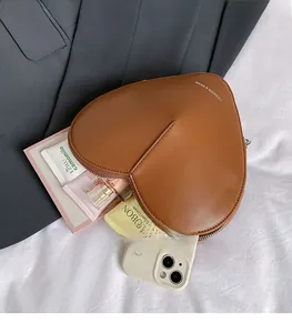 Vue de dessus de l'intérieur spacieux du sac en cuir marron en forme de cœur avec objets