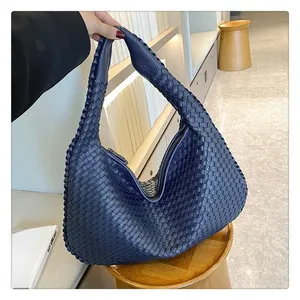 Primo piano dettagliato della trama in pelle intrecciata a mano su questa borsa hobo blu