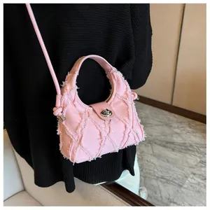 Detailed view of pink quilted denim handbag with silver twist lock and frayed fabric texture