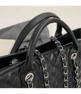 Detail of black quilted leather handbag featuring silver chain strap and durable handle