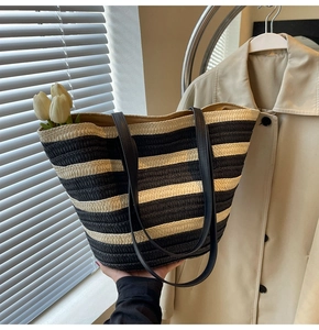 Detail of black and white striped straw tote bag featuring woven texture and slim handles