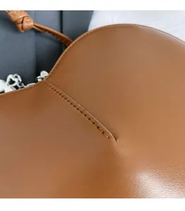 Gros plan sur le cuir caramel et les surpiqûres détaillées d'un sac à bandoulière chic