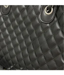Close-up of black quilted leather tote showing silver metal handle and refined texture