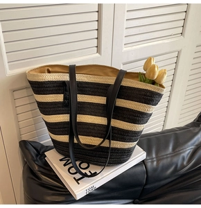 Close-up of black and white striped straw tote bag with premium leather handles