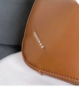 Détail du sac en cuir marron texturé avec fermeture éclair argentée et texte Fashion & Bags
