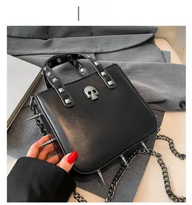 Close-up of gothic black handbag with silver skull relief and sharp metallic spikes