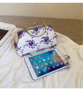 Lace chain bag detail showing capacity with a tablet and purple floral embroidery