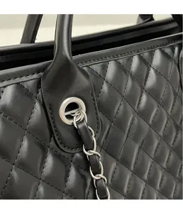 Detail of silver metal eyelets and leather-woven chain strap on quilted black tote