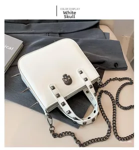 Close-up of gothic white handbag featuring black metal skull and studded spiked handles