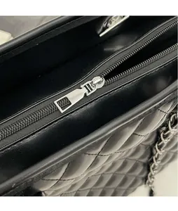 Detailed close-up of smooth silver zipper hardware on black quilted leather handbag