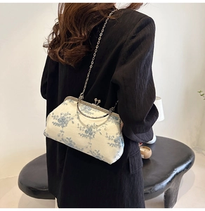 Detail of vintage evening bag with blue floral embroidery and retro metal clasp