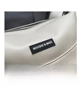 Close-up of pebble grain leather texture and metallic logo on beige shoulder bag