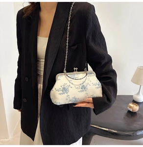 Detail of vintage white handbag with light blue floral embroidery and silver metal handle