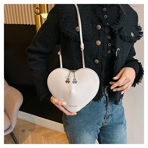 Vue détaillée du sac bandoulière blanc en cuir en forme de cœur avec zips trèfles en métal