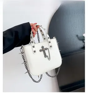 Detail of white gothic handbag featuring silver cross pendant and punk metal spikes chains