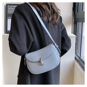 Borsa a sella azzurra con fibbia argento indossata da una modella per lo stile