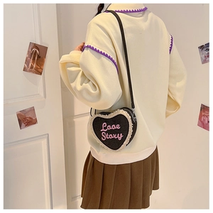 Détail du sac à bandoulière en forme de cœur avec bordure en peluche et broderie