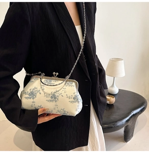 Detail of vintage floral embroidery on a cream evening bag with silver metal frame