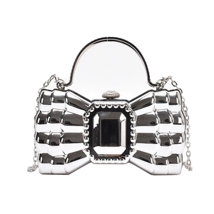 Silver bow-shaped evening clutch bag with metallic finish, rhinestone details, and chain strap
