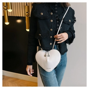 Détail du sac à bandoulière en forme de cœur avec pendentif trèfle et lettrage