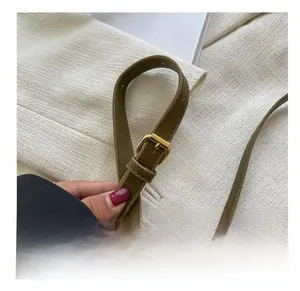 Détail de la bandoulière réglable en cuir vert olive avec boucle dorée et couture
