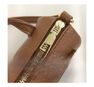 Close-up of golden zipper hardware on brown pebbled leather shoulder handbag detail