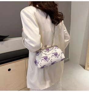 Detail of vintage white embroidery handbag featuring purple flowers and silver chain