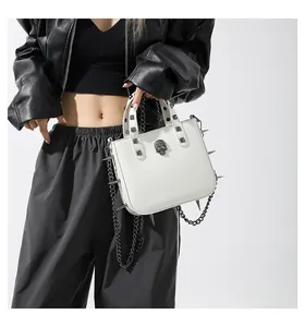 Close-up of white gothic handbag with silver metal studs, spikes and skull ornament