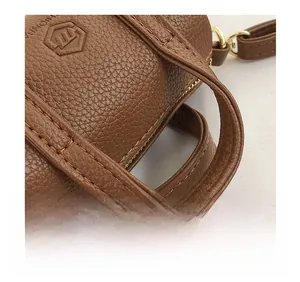 Macro detail of dark brown pebble leather handbag with gold metal hardware and stitching