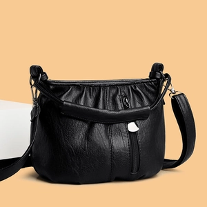 Chic black pleated crossbody bag with silver zippers on elegant orange background