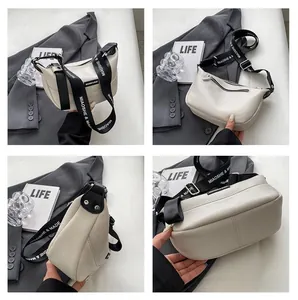 Detail view of cream dumpling crossbody bag with lychee texture and branded strap