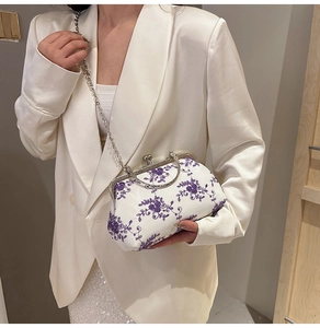 Detailed close-up of exquisite purple flower embroidery on a cream vintage evening bag